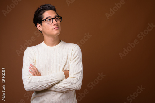 Young multi-ethnic handsome man against brown background © Ranta Images