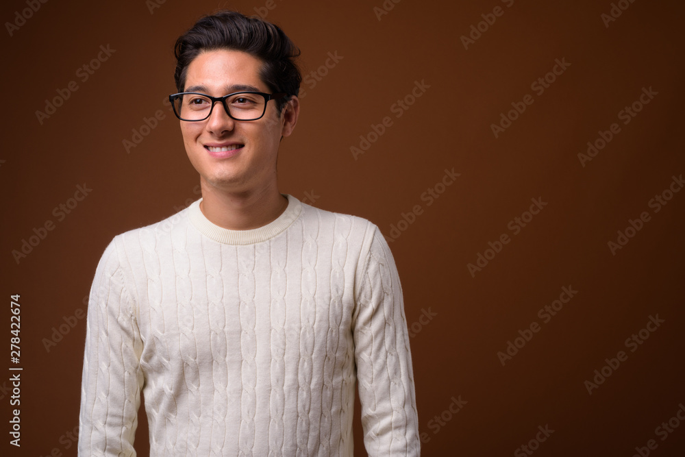Obraz premium Young multi-ethnic handsome man against brown background