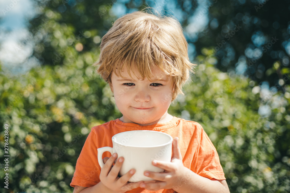 Children holidays on nature background. Drink milk with white cup. Cute child. Children holidays on nature background. Drink milk with white cup. Cute child.
