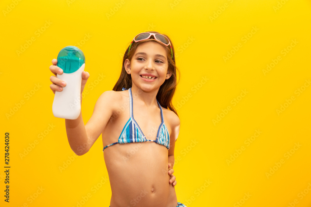 Child holding a bottle of sunscreen on white. Introducing a product. Concept of summer, beach and pool. Child holding a bottle of sunscreen on white. Introducing a product. Concept of summer, beach and pool.