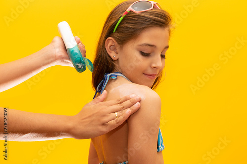Mother applying sunscreen on her daughter. Concept of summer, beach and pool.