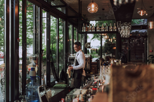 Handsome barman in apron working in coffee shop