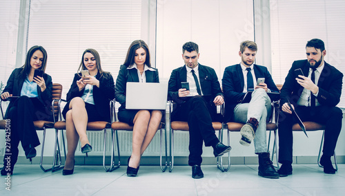 business team with laptop and smartphone sitting on the sofa in