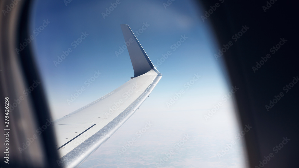 View from the window on the wing of the aircraft and the beautiful blue sky. Aircraft window. The concept of traveling by plane