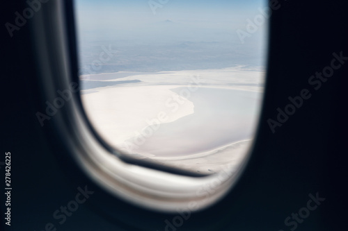 View from the window of the aircraft on the landscapes below, mountains, lakes, forests, seas. Aircraft window. The concept of traveling by plane. Travel, nature, views, landscape concepts