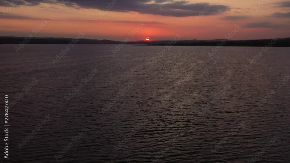 Sea panorama with quiet water surface in the orange-pink light of a sunny day's sunset aerial view drone slide. Flocks of ducks swim in the water in the evening. Bright disc of the setting sun Sea panorama with quiet water surface in the orange-pink light of a sunny day's sunset aerial view drone slide. Flocks of ducks swim in the water in the evening. Bright disc of the setting sun
