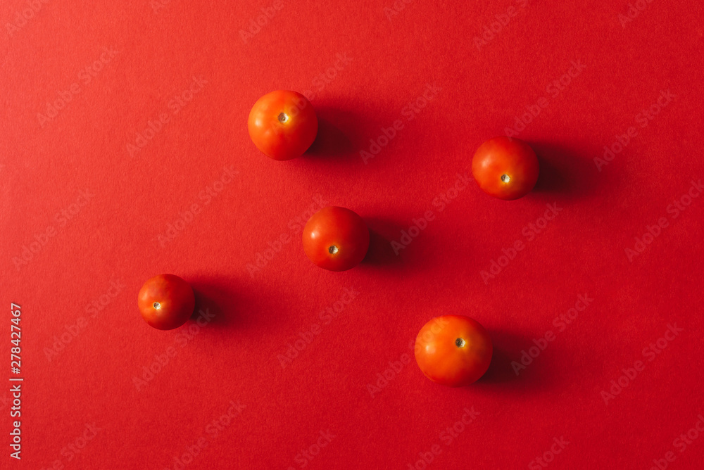 Five cherry tomatoes on a red background. Flat lay. Five cherry tomatoes on a red background. Flat lay.