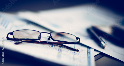 Business Financial Analysis workplace, glasses lie on documents