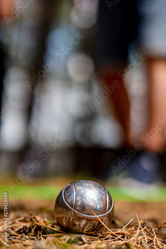 Close up of metallic petanque ball on the ground against the blurred background.Sport, relax, recreation and leisure concept/Petanque ball on the ground