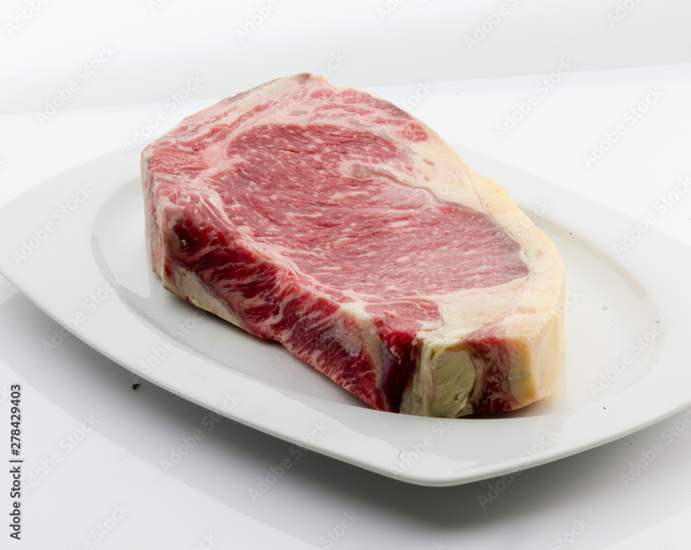  plato de porcelana blanca con Chuletón de vaca cruda y fresca. white porcelain plate with raw and fresh beef T-bone steak.