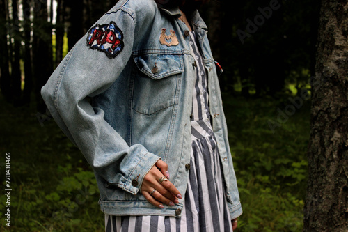 Girl in denim jacket and striped dress in forest