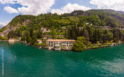 Fototapeta Naklejka Na Ścianę i Meble -  Beautifull aerial panoramic view from the drone to Varenna famous old Italy town on bank of Como lake. High top view to villa Monastero landscape, green hills, mountains and city in sunny summer day