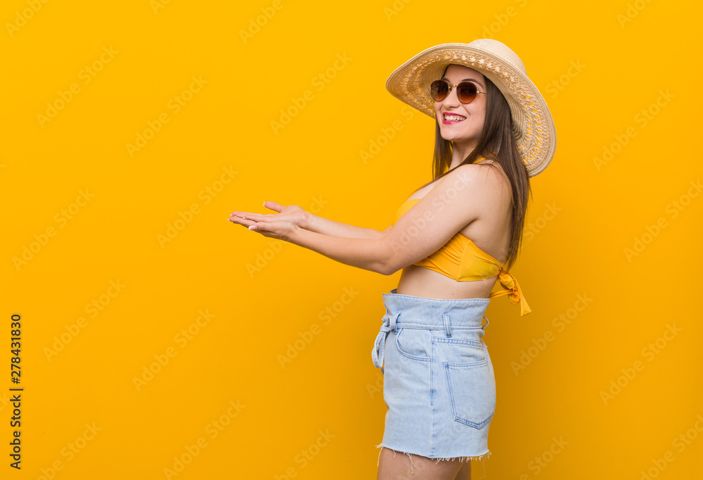 Young caucasian woman wearing a straw hat, summer look holding a copy space on a palm. Young caucasian woman wearing a straw hat, summer look holding a copy space on a palm.