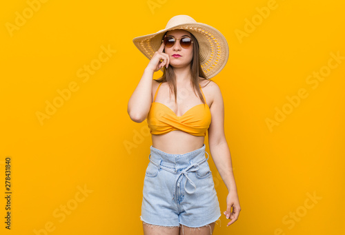 Young caucasian woman wearing a straw hat, summer look pointing temple with finger, thinking, focused on a task.