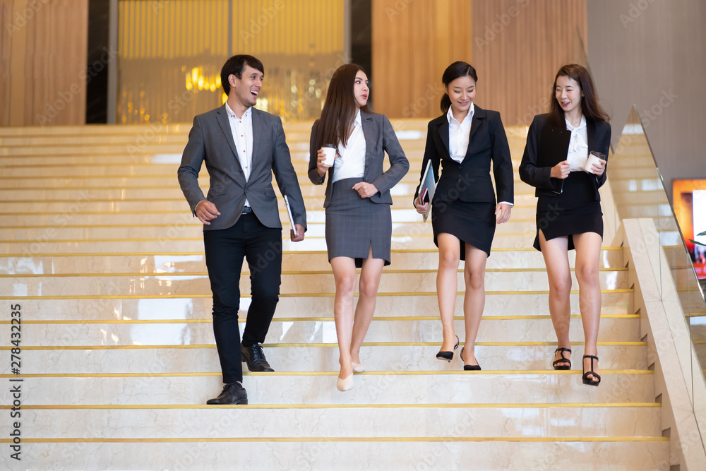 Asian business people  walking in office building. Young businessman and businesswoman talking when walking.