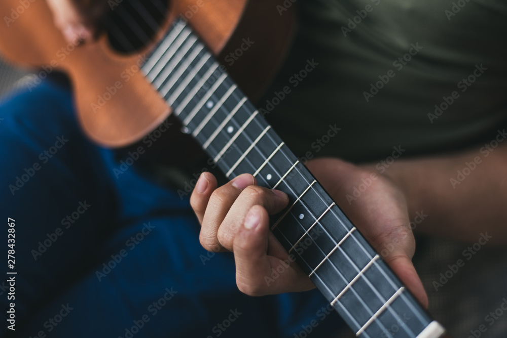 ukulele game. a man playing a little guitar. the performer writes the music on the ukulele at home