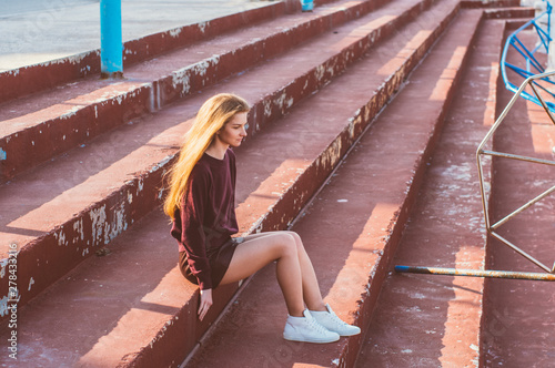 Young blonde girl in skirt sitting on painted stairs