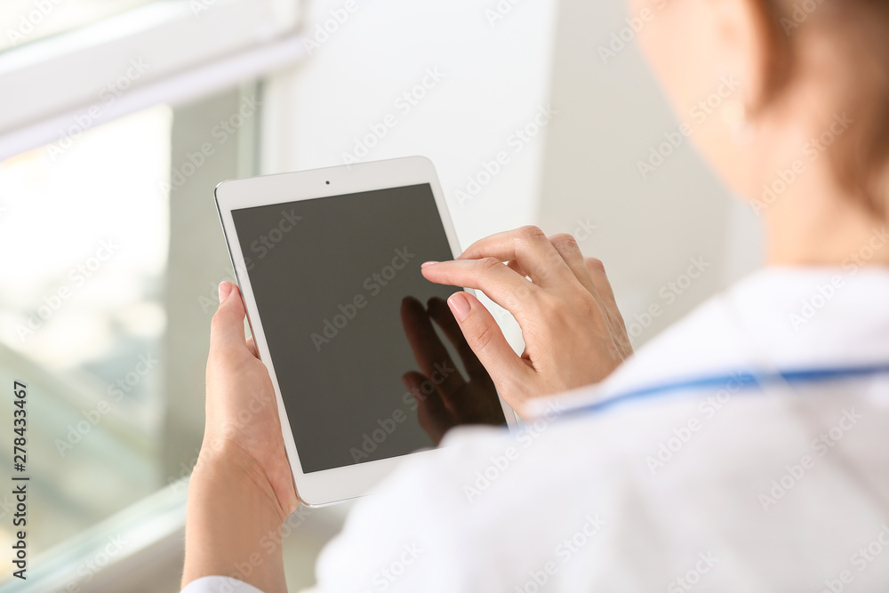 Female doctor using modern tablet computer in clinic, closeup