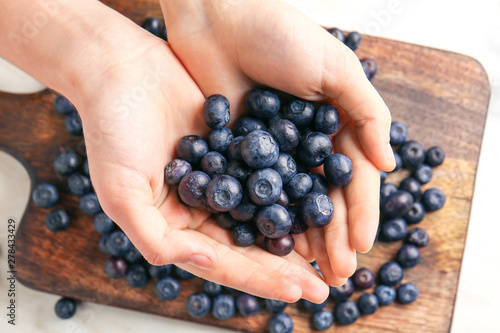 Female hands with heap of fresh blueberry, closeup