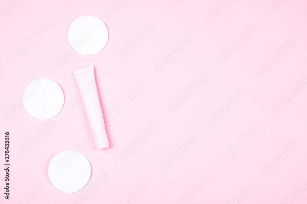 Pink cosmetic tube and white cotton pads.