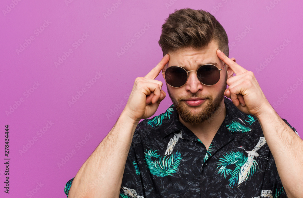 Young man wearing a vacation look focused on a task, keeping him forefingers pointing head. Young man wearing a vacation look focused on a task, keeping him forefingers pointing head.
