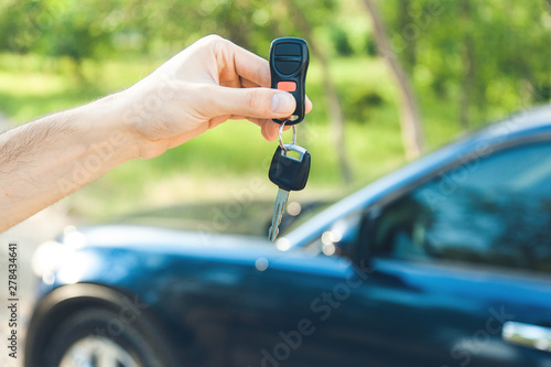 man hand key and car in nature