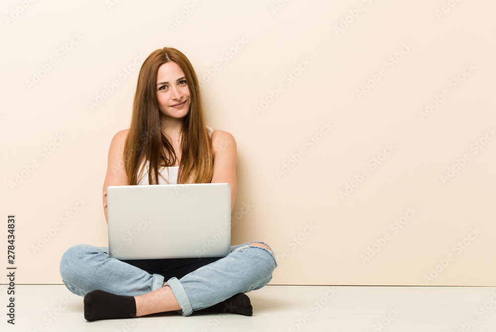 Naklejka premium Young ginger woman sitting on her house floor who feels confident, crossing arms with determination.