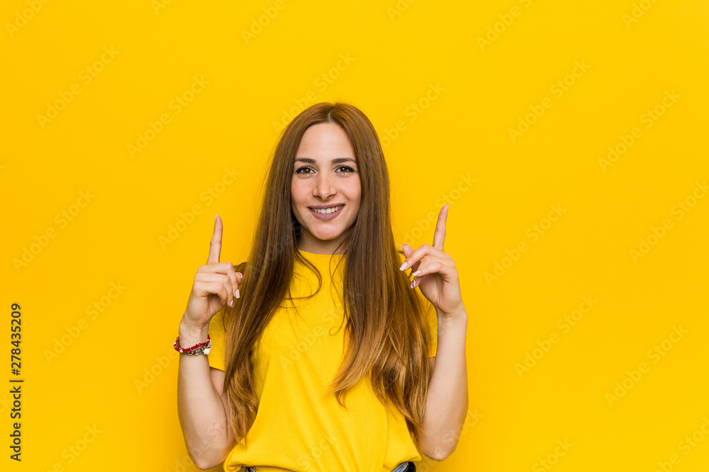 Young ginger redhead woman indicates with both fore fingers up showing a blank space. Young ginger redhead woman indicates with both fore fingers up showing a blank space.