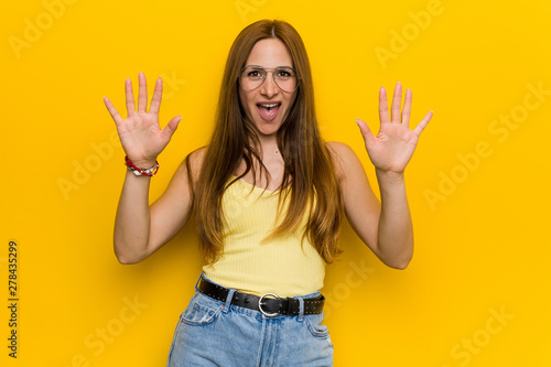 Young redhead ginger woman with freckless showing number ten with hands.