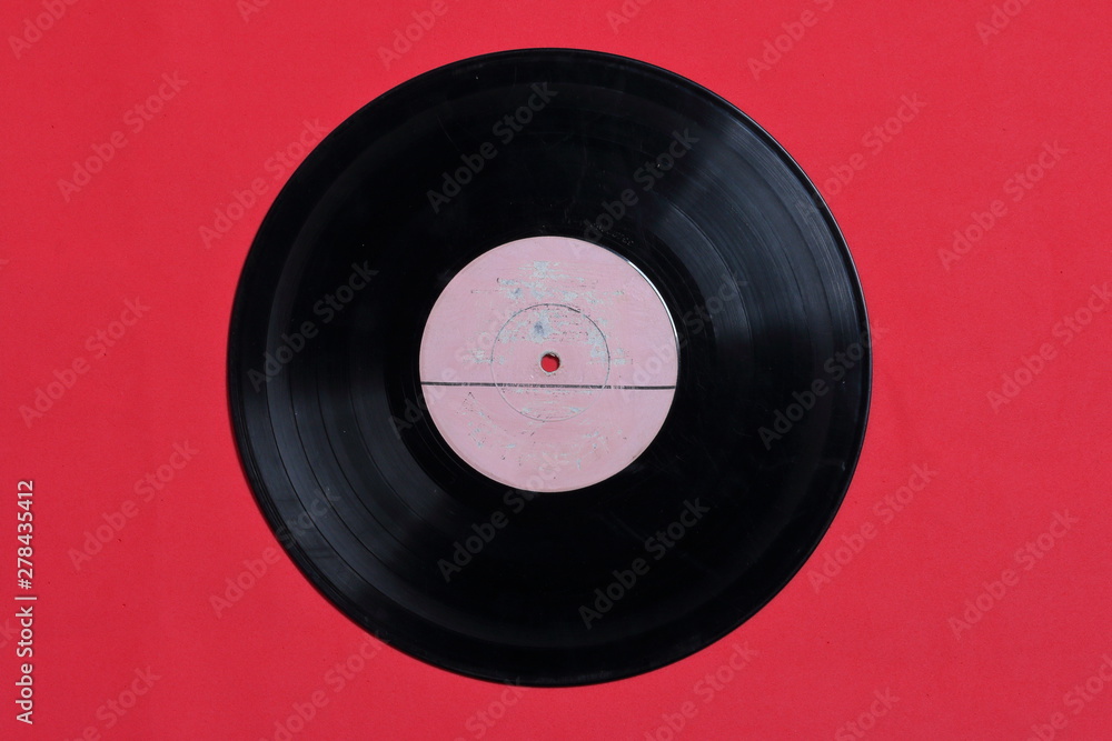 Fototapeta premium Old vinyl record. Worn and dirty. They lie on the surface of coral color.