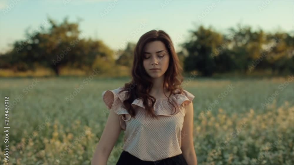 Portrait of a beautiful girl walking in the field. The girl moves away from the camera and smiles Portrait of a beautiful girl walking in the field. The girl moves away from the camera and smiles