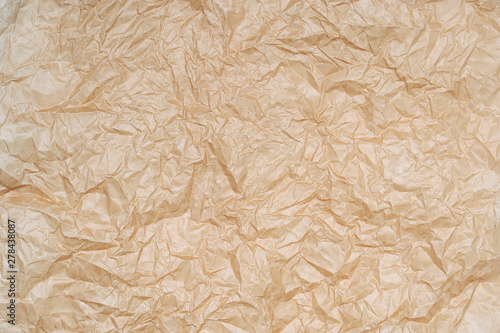 Texture of crumpled parchment paper. Background of creased brown backing paper. Crumpled paper texture.