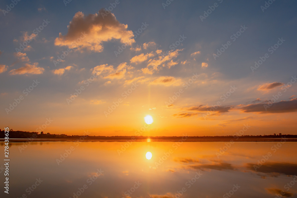 Obraz premium Sunset reflection lagoon. beautiful sunset behind the clouds and blue sky above the over lagoon landscape background. dramatic sky with cloud at sunset