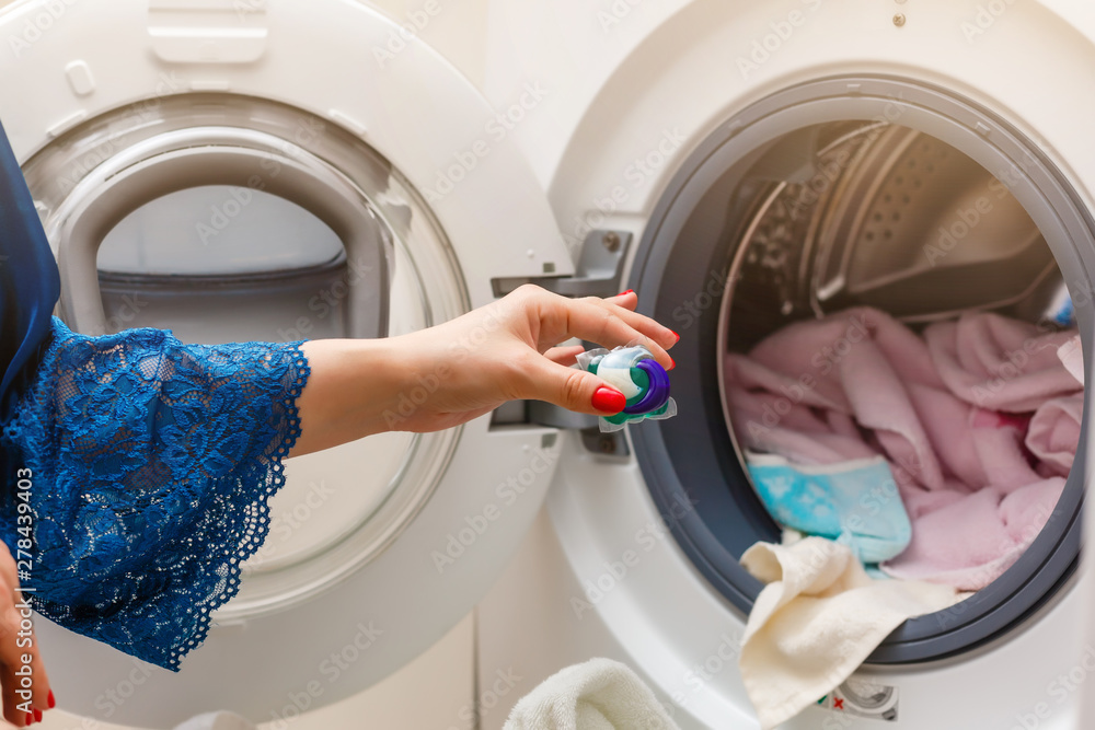 A close up of a young wife putting a cloth into washing machine A close up of a young wife putting a cloth into washing machine