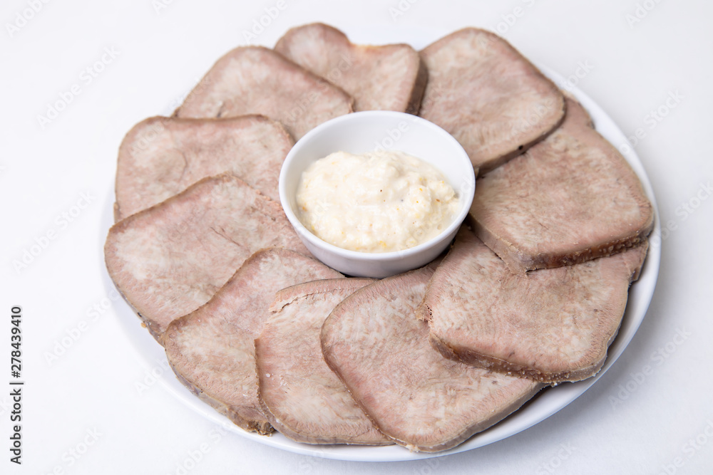 Beef boiled tongue with horseradish on a white plate. White background, isolated. Close-up. Beef boiled tongue with horseradish on a white plate. White background, isolated. Close-up.