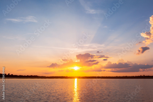 Sunset reflection lagoon. beautiful sunset behind the clouds and blue sky above the over lagoon landscape background. dramatic sky with cloud at sunset © Achira22
