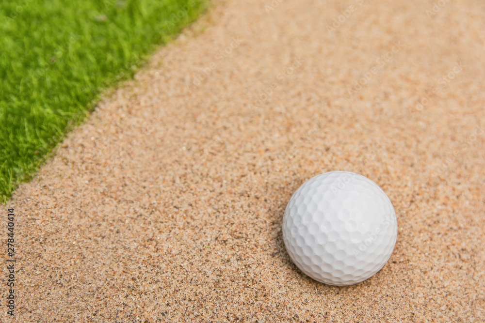 White golf ball in sand bunker on golf court.