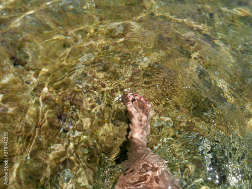 piedi di donna si intravedono nell'acqua del mare limpido e trasparente photo