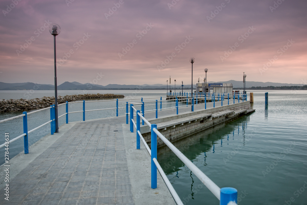 Obraz premium Sunset at Lake Trasimeno. Fisherman on the Castiglione del Lago pier during the summer sunset, Trasimeno Lake, Umbria, Italy