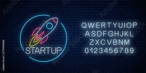 Glowing neon sign of business project startup with alphabet. Business fast start symbol flying rocket in neon style