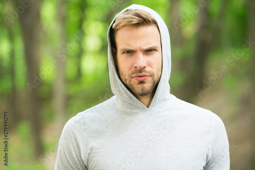 macho man. man in hood. casual style. male fashion. unshaven guy outdoor. seriousness and masculinity. sportswear fashion. sportsman relax after training outdoor. handsome unshaven man in hood
