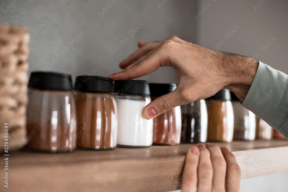 close up. a man takes spices from the kitchen shelf - obrazy, fototapety, plakaty 