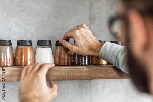 Fototapeta Naklejka Na Ścianę i Meble -  close up. a man takes spices from the kitchen shelf