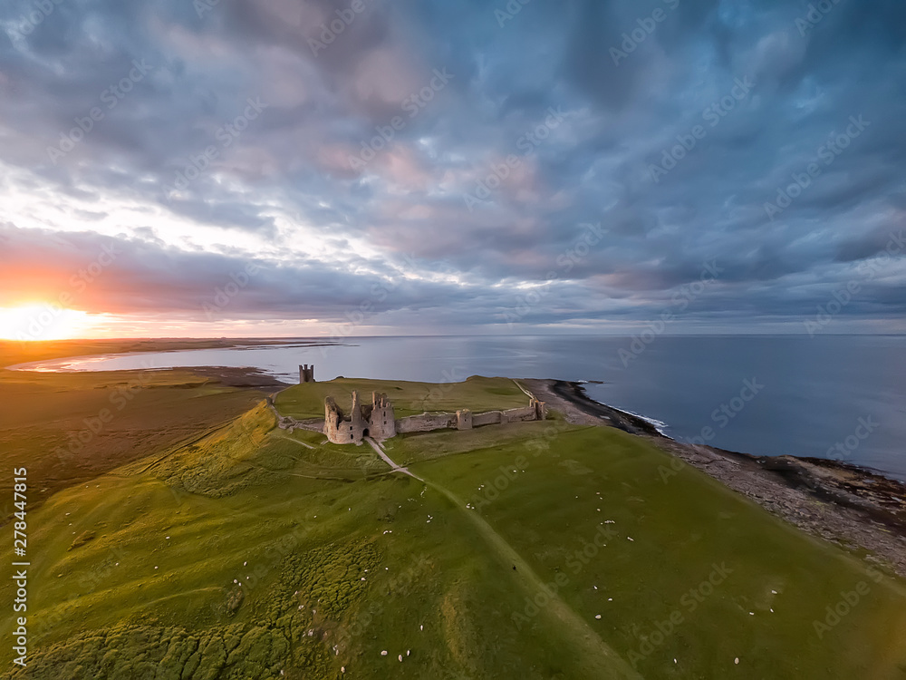Φωτογραφία View from the air to  Embleton bay, North sea, the cliff, ruins and green fields with flock of sheep