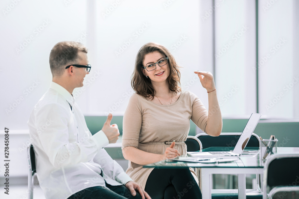 side view. business colleagues discuss something sitting at the Desk side view. business colleagues discuss something sitting at the Desk
