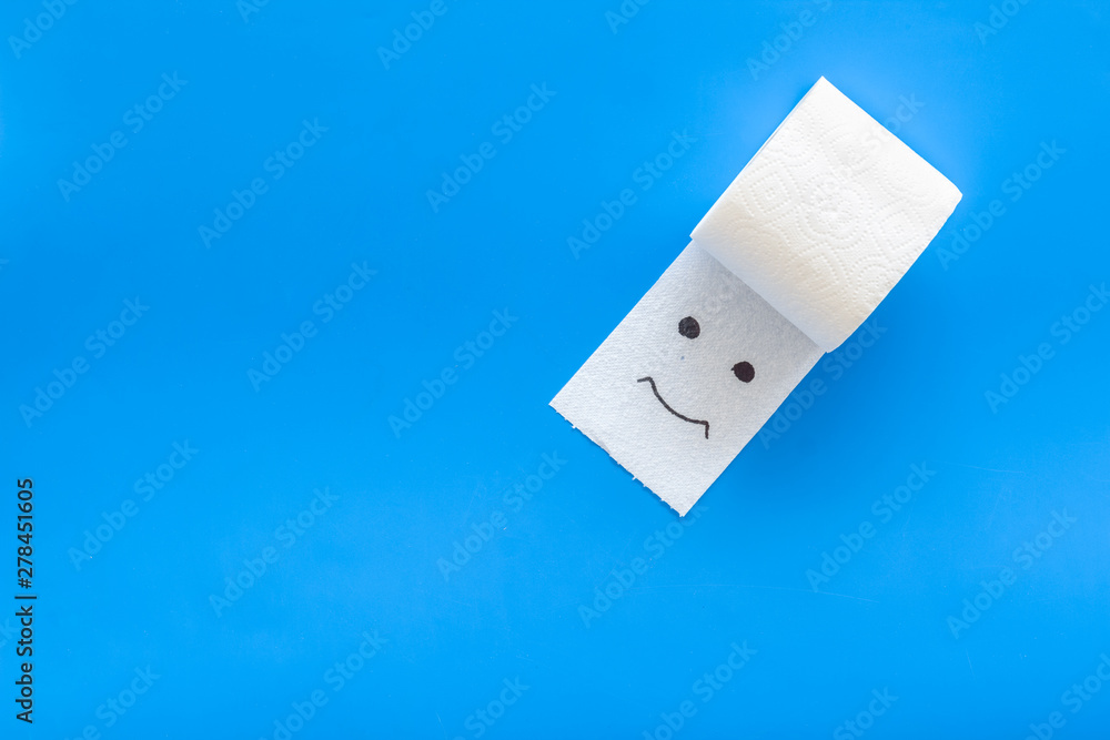 Fototapeta premium Proctology concept with toilet paper roll and painted face on blue background top view mock up