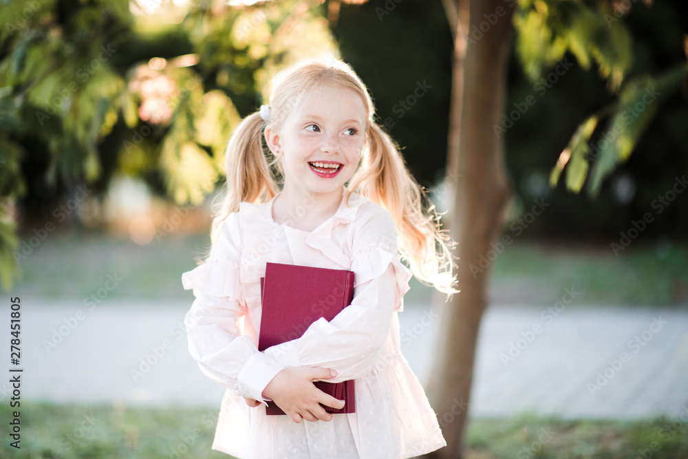 Happy child girl 5-6 year old holding books outdoors over nature background. Back to school. Happy child girl 5-6 year old holding books outdoors over nature background. Back to school.