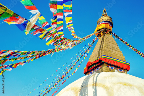 Bodhnath stupa in kathmandu with buddha eyes and prayer flags on clear Blue sky background.