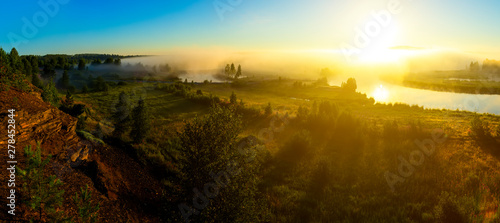 Beautiful rural landscape in morning fog at sunrise. Temple on the river bank at sunrise, reflected in river. Traditional Russian landscape. Chusovaya river, Ural, Russia