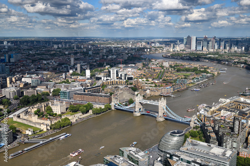 Aerial view of the muddy River Thames with Tower of London Castle, Tower Bridge, modern curved City Hall and Canary Wharf skyscrapers London England